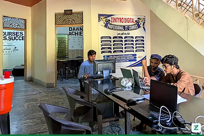 Students working on laptops in the Zentyro Digital lab in Multan, under the Professional IT Courses banner