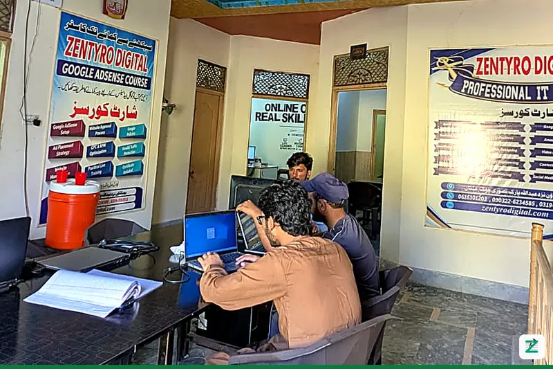 Students practicing on laptops at the Zentyro Digital training lab in Multan, with Google AdSense and Professional IT course posters